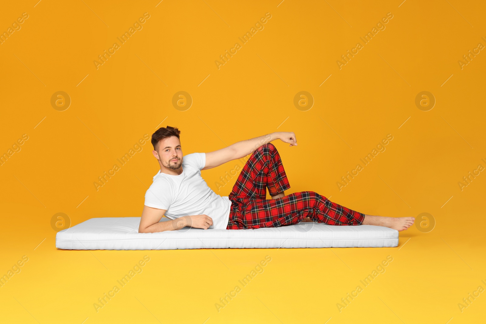 Photo of Man lying on soft mattress against orange background