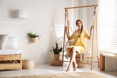 Beautiful woman resting in hammock chair at home