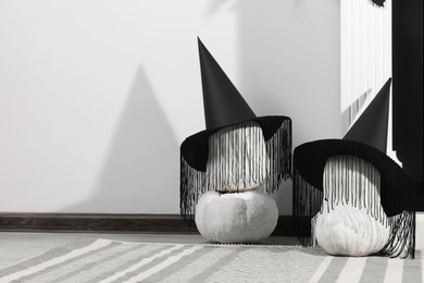Beautiful black witch hats on pumpkins indoors, space for text. Halloween celebration