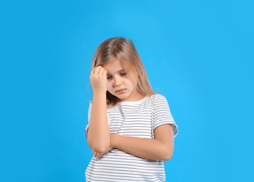 Upset little girl on light blue background