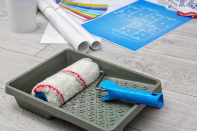 Photo of Roller brush in paint tray for interior decorating on floor