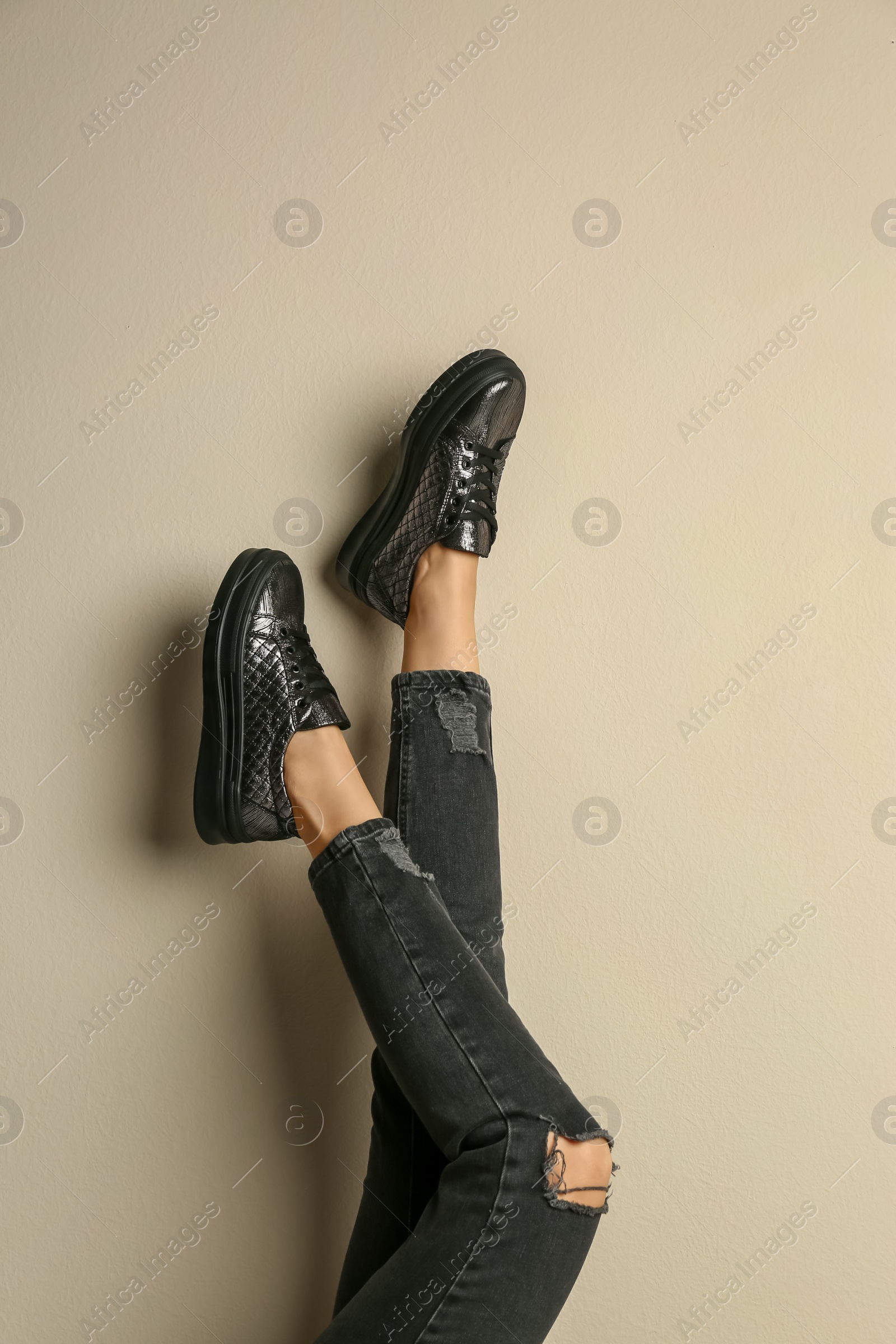 Photo of Woman wearing shoes on beige background, closeup