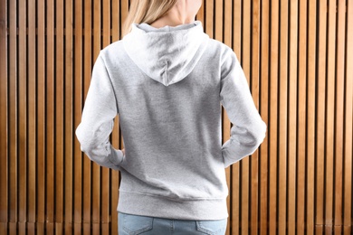 Woman in hoodie sweater on wooden background. Space for design