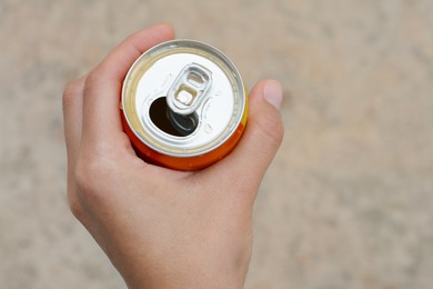 Photo of Woman holding tasty open canned beverage against blurred background, top view