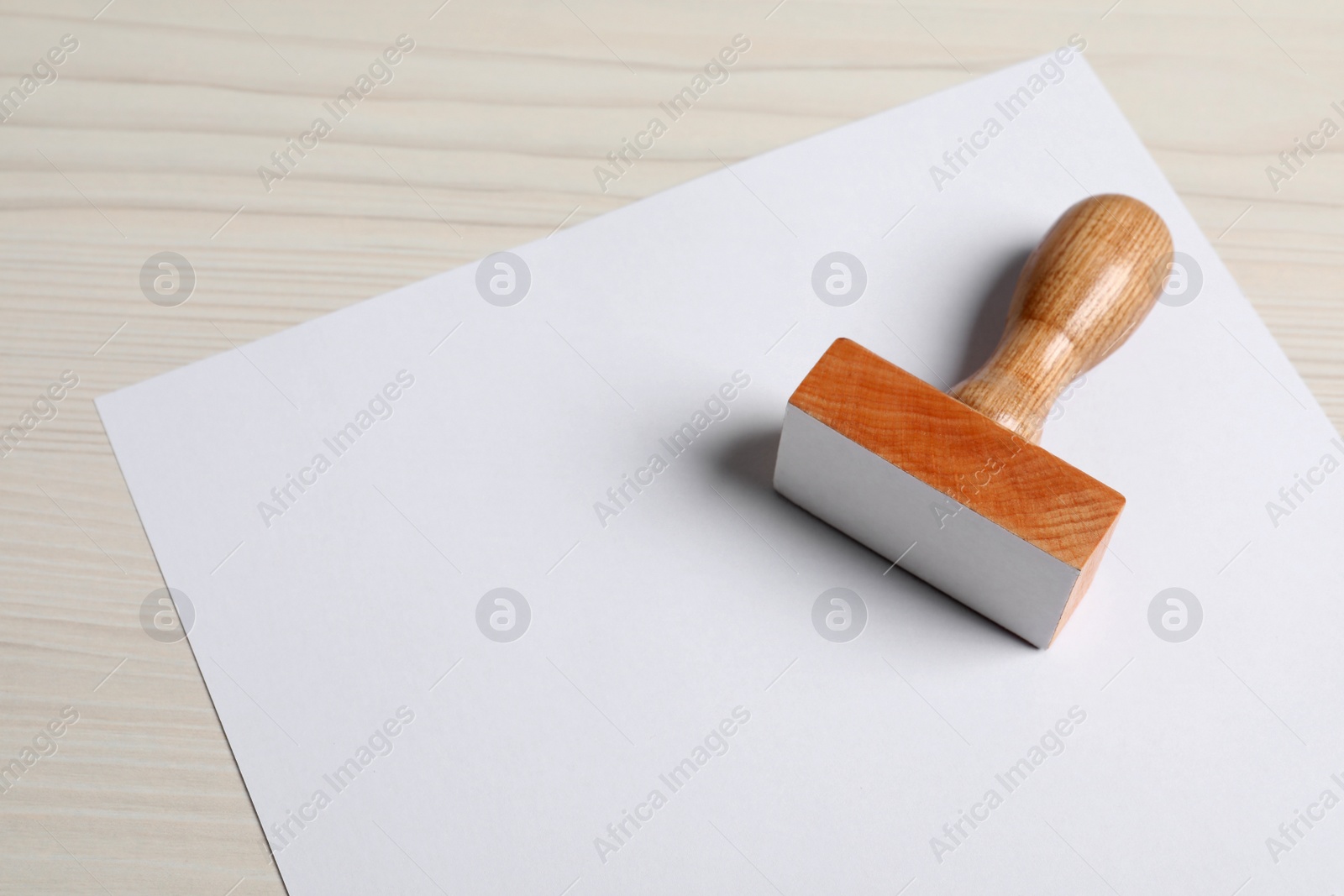 Photo of Blank sheet of paper and visa stamp on white wooden table