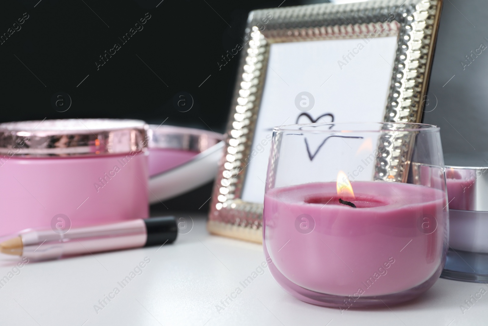 Photo of Stylish dressing table with different cosmetic products and burning candle