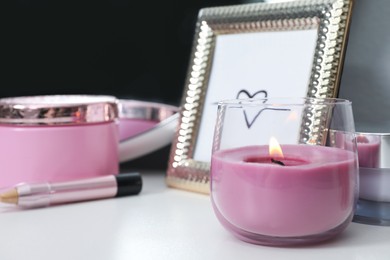 Photo of Stylish dressing table with different cosmetic products and burning candle