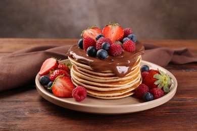 Photo of Stack of tasty pancakes with fresh berries and chocolate spread on wooden table