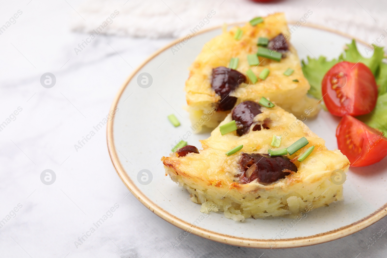 Photo of Tasty sausage casserole with green onions and vegetables served on white marble table, closeup. Space for text