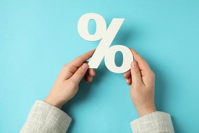 Photo of Man holding percent sign on light blue background, top view