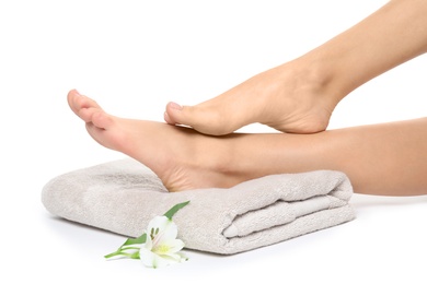 Photo of Woman with smooth feet, flower and towel on white background, closeup. Spa treatment