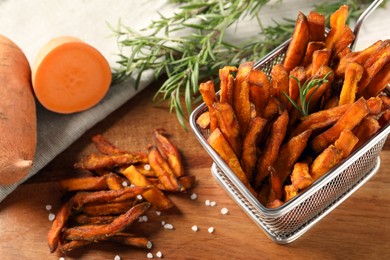 Photo of Sweet potato fries and rosemary on wooden table, above view