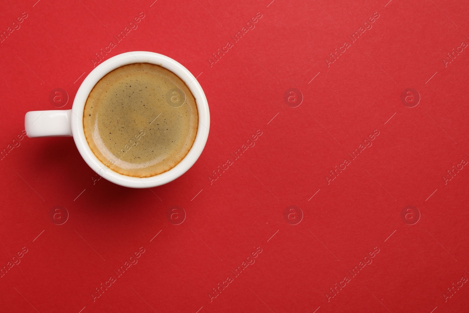 Photo of Aromatic coffee in cup on red background, top view. Space for text