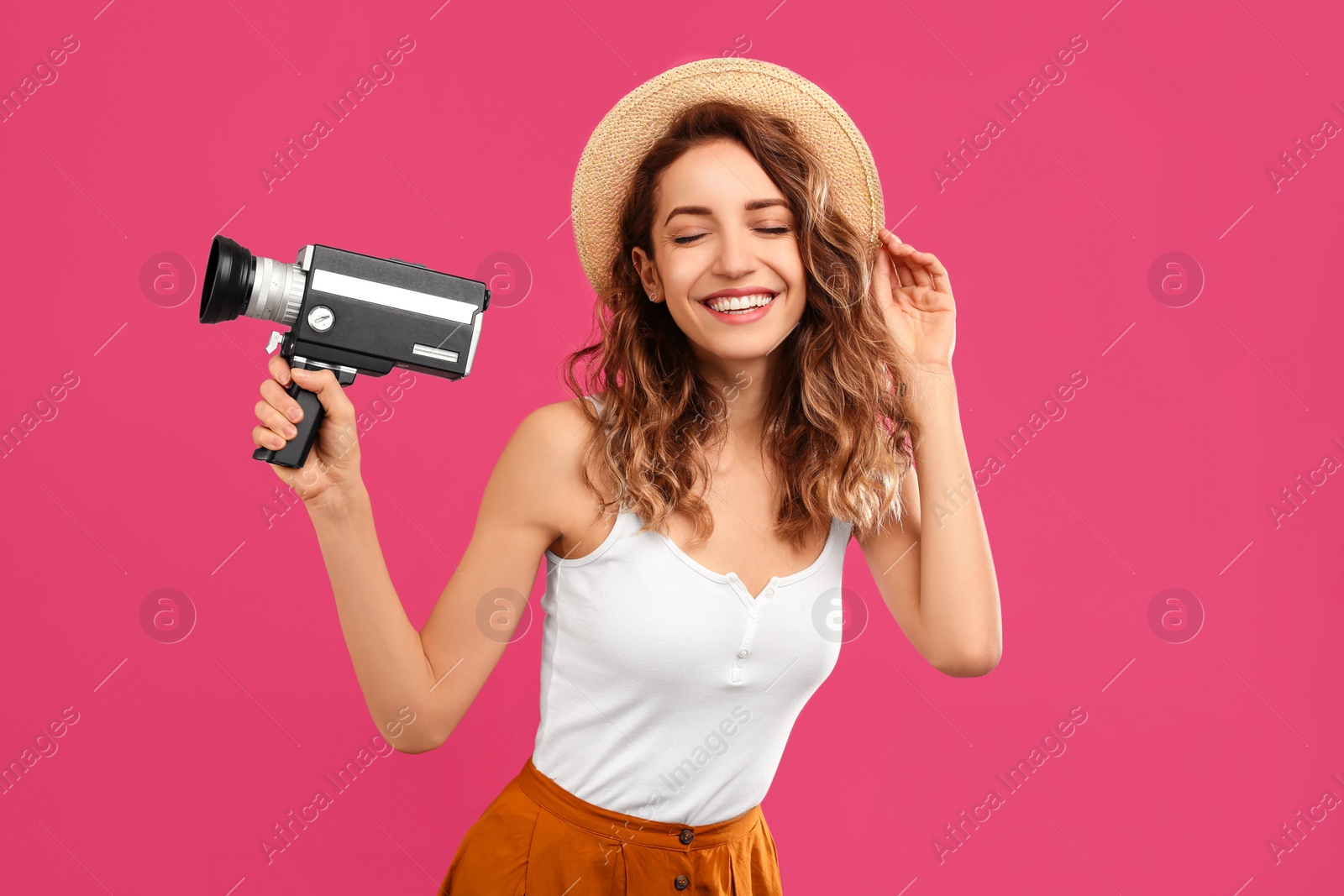 Photo of Beautiful young woman with vintage video camera on crimson background