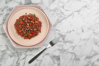 Photo of Tasty brown rice served on marble table, flat lay. Space for text