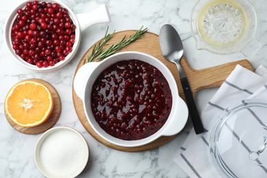 Photo of Fresh cranberry sauce in bowl served on white marble table, flat lay
