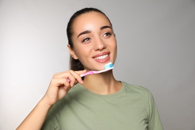 Woman holding toothbrush with paste on light background