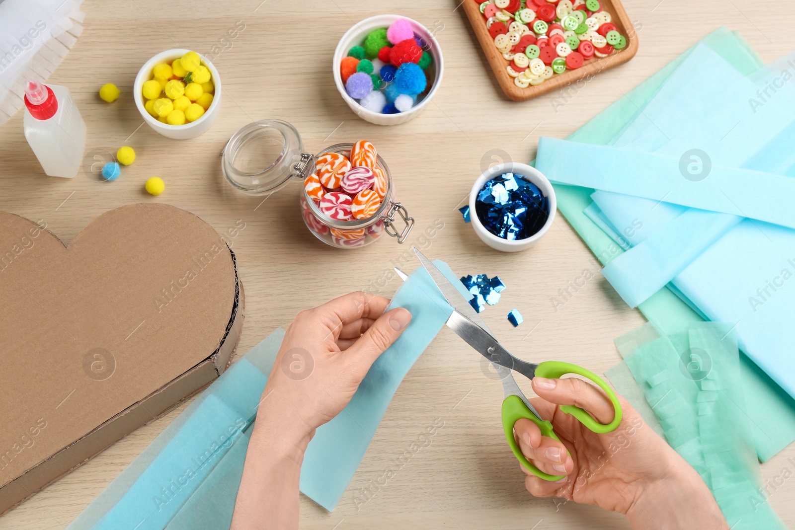 Photo of Woman decorating cardboard cloud at wooden table, top view. Pinata diy