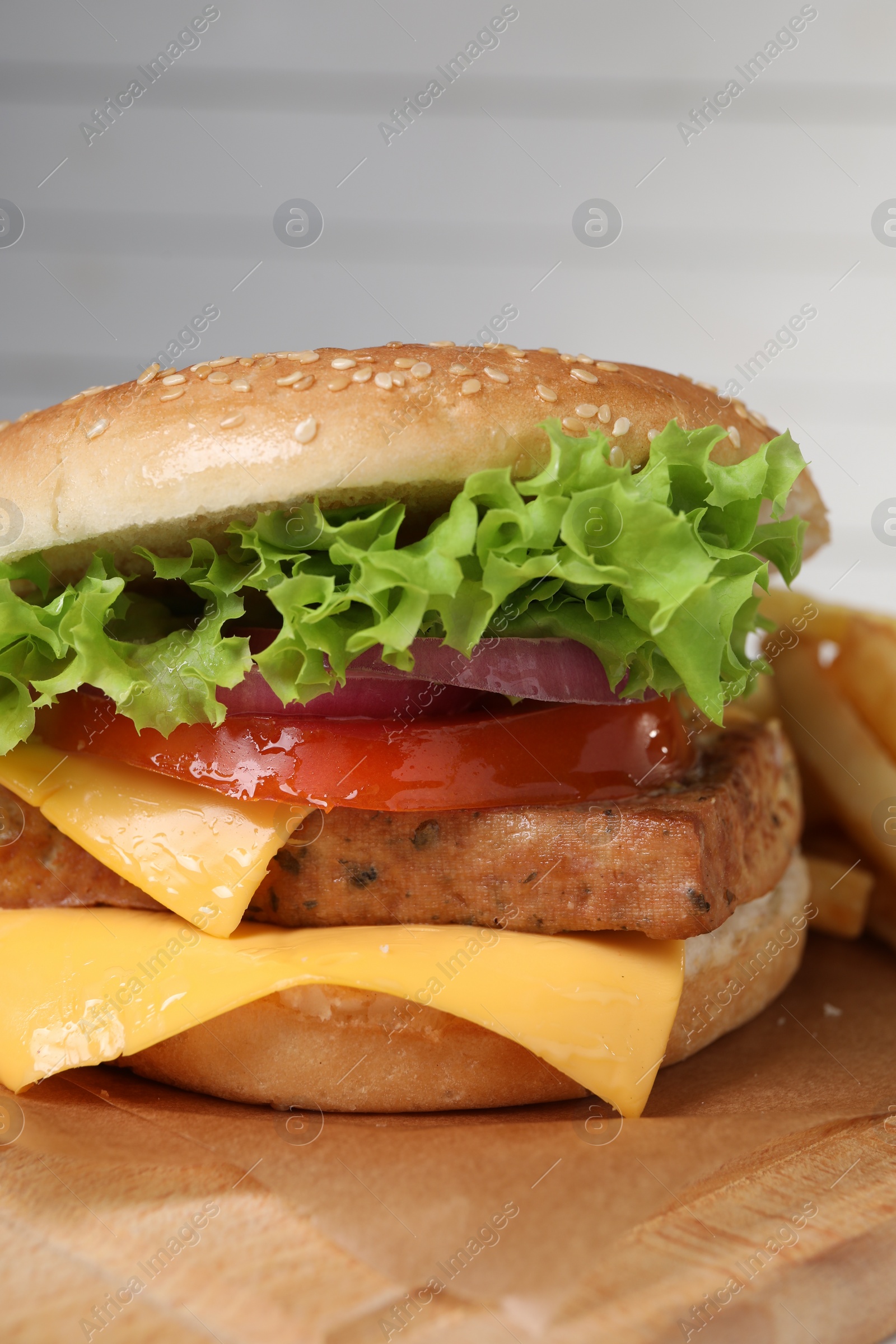 Photo of Delicious burger with tofu and fresh vegetables on wooden table, closeup