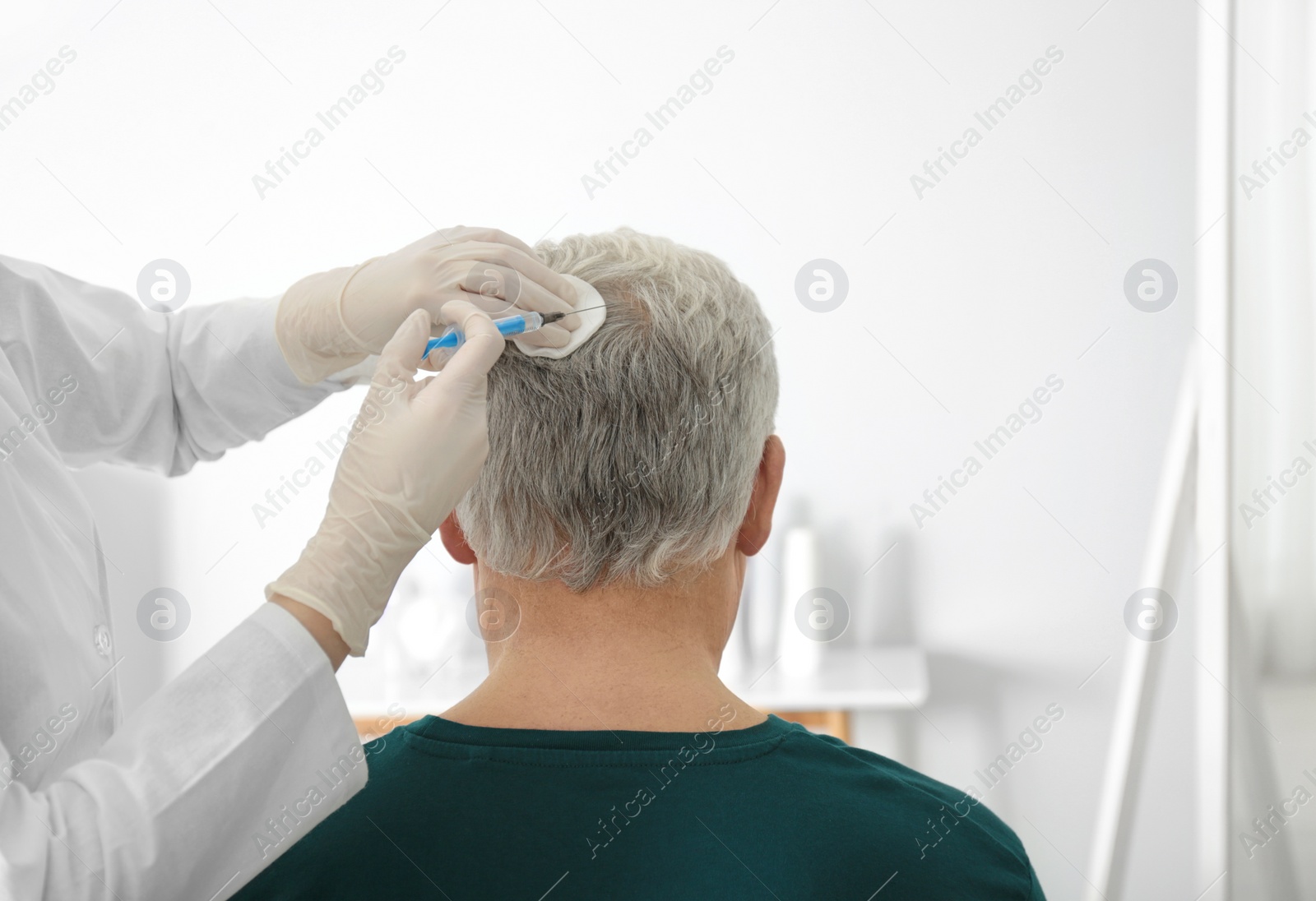 Photo of Senior man with hair loss problem receiving injection in salon