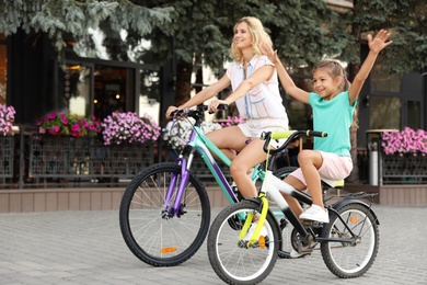 Happy mother with daughter riding bicycles in city