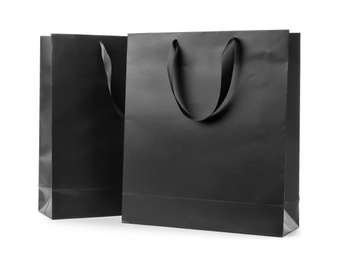 Photo of Paper shopping bags with ribbon handles on white background. Mockup for design