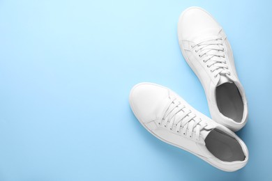 Photo of Pair of stylish white sneakers on light blue background, top view. Space for text