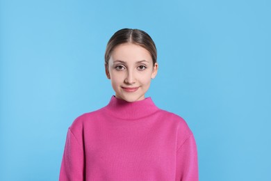 Portrait of beautiful teenage girl on light blue background