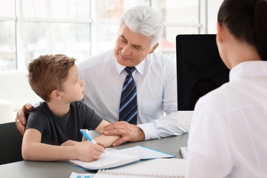 Photo of Senior man with his grandson having appointment at child psychologist office