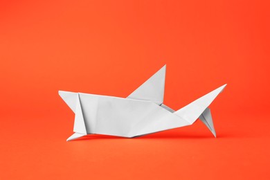 Photo of Origami art. Handmade white paper shark on orange background