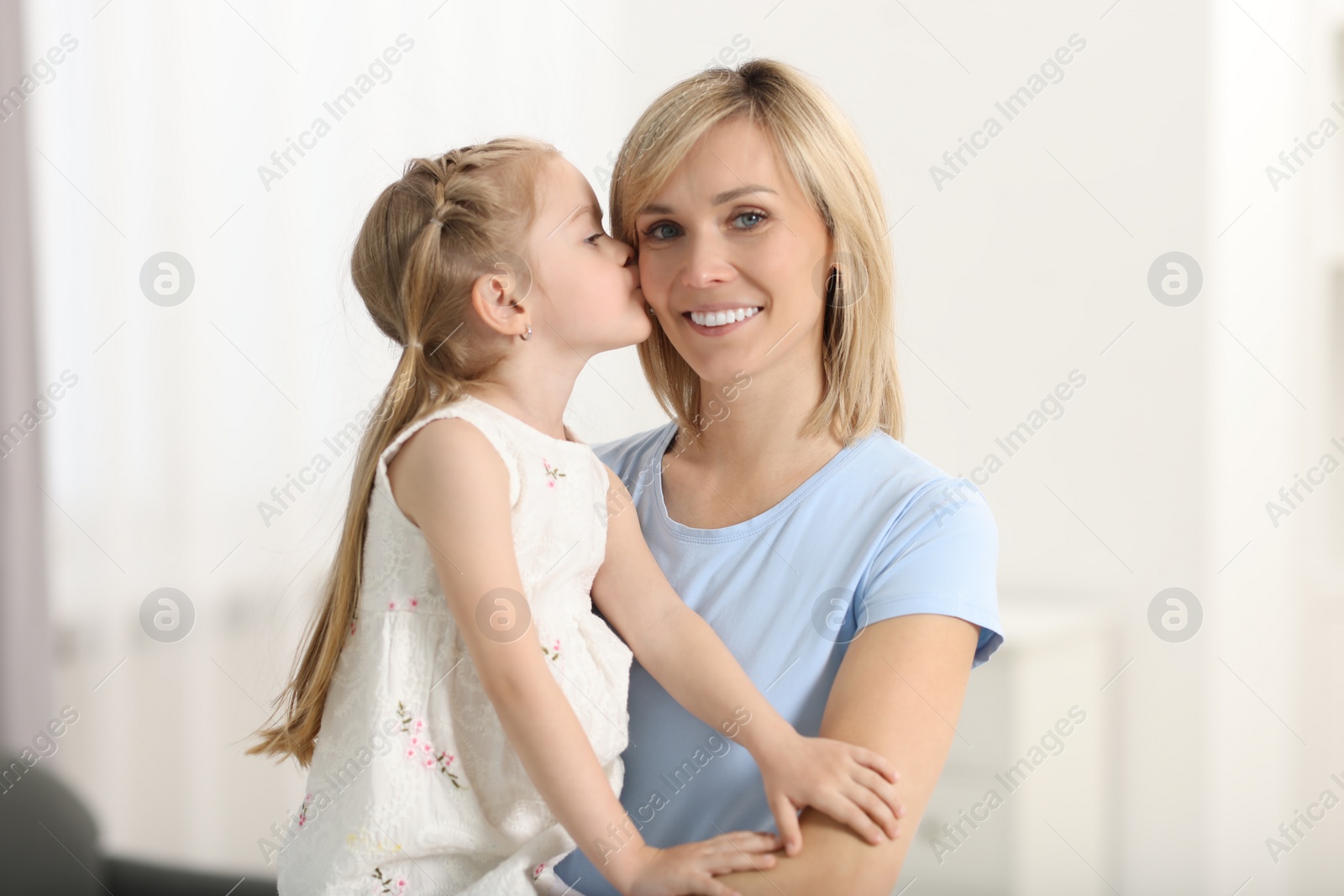 Photo of Daughter kissing her happy mother at home