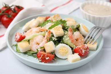 Photo of Delicious Caesar salad with shrimps on white table, closeup