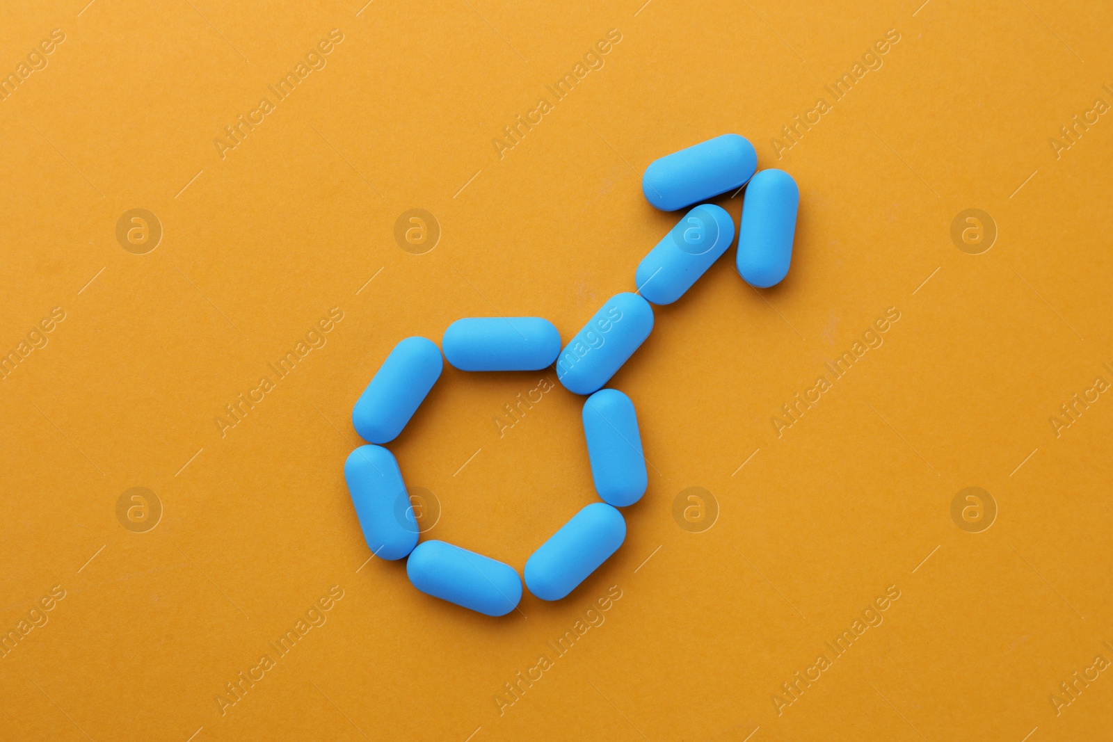 Photo of Pills on orange background, top view. Potency problem