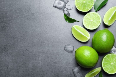 Photo of Fresh ripe limes and ice cubes on gray background, top view
