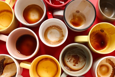 Many dirty cups after drinking coffee on red table, flat lay