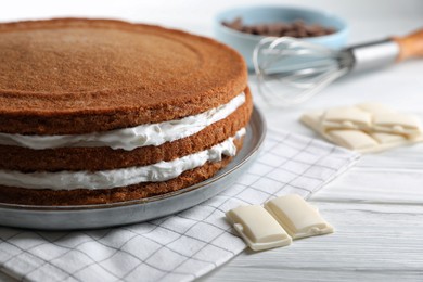 Delicious homemade layer cake and chocolate on white wooden table, closeup