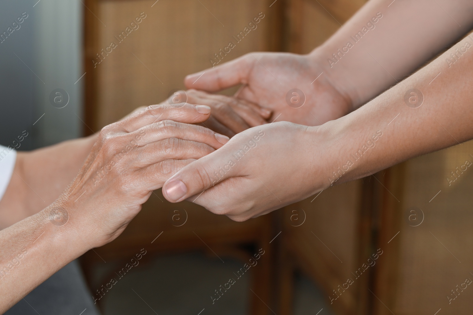 Photo of Caregiver helping elderly woman at home, closeup