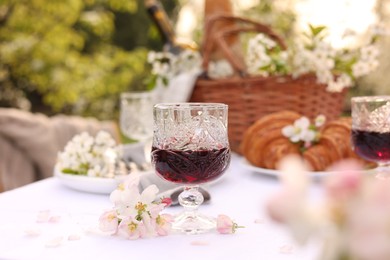 Stylish table setting with beautiful spring flowers, wine and croissants in garden