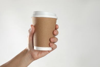 Woman holding takeaway paper coffee cup on white background, closeup. Space for text