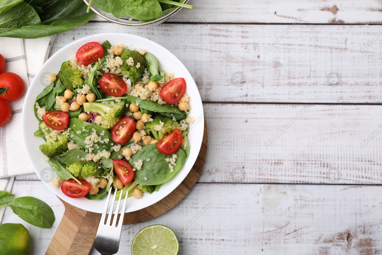 Photo of Healthy meal. Tasty salad with quinoa, chickpeas and vegetables on white wooden table, flat lay with space for text