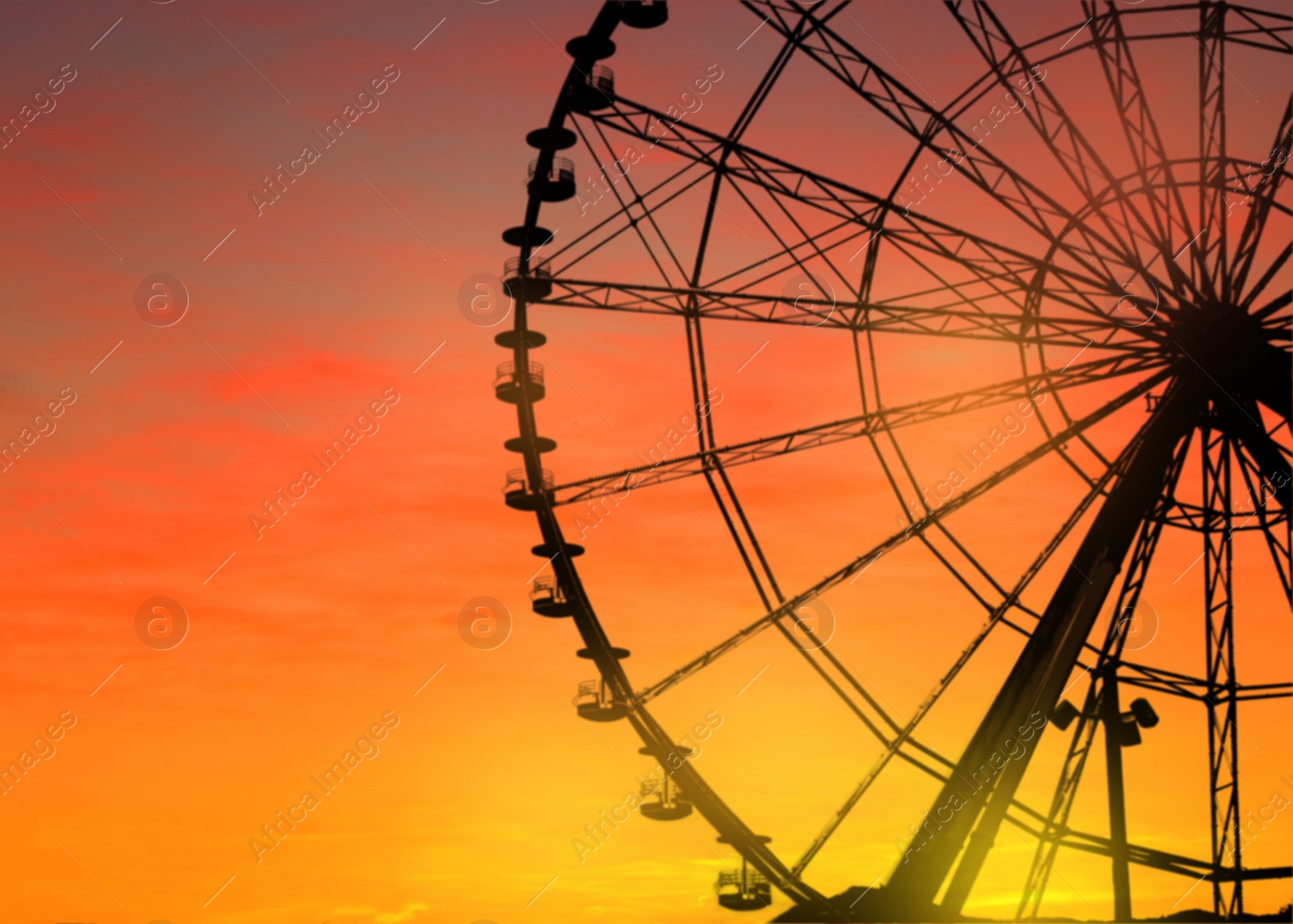 Image of Beautiful large Ferris wheel outdoors at sunset