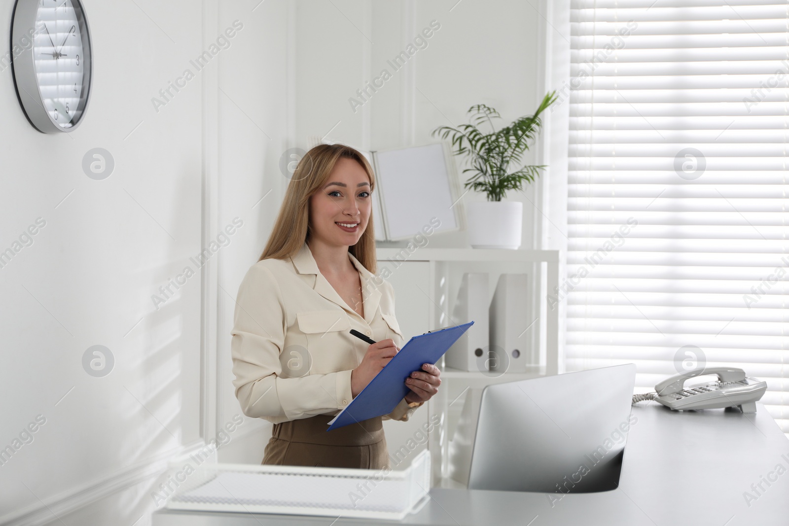 Photo of Receptionist with clipboard at countertop in office