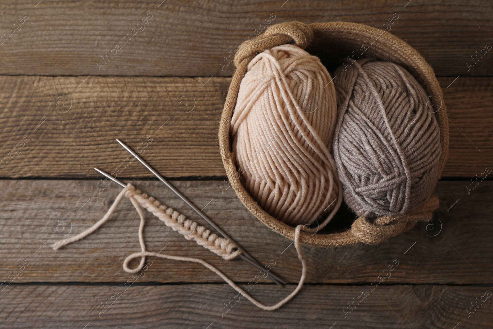 Photo of Soft colorful yarns, knitting and metal needles on wooden table, top view