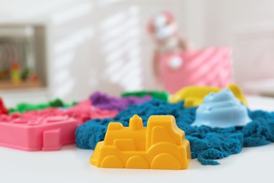 Photo of Bright kinetic sand and toys on white table indoors