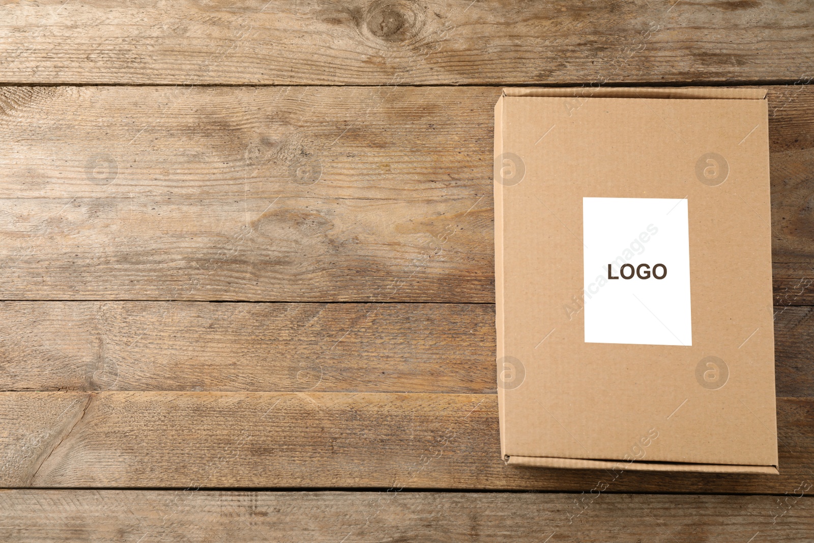 Image of Closed cardboard box with logo on wooden background, top view