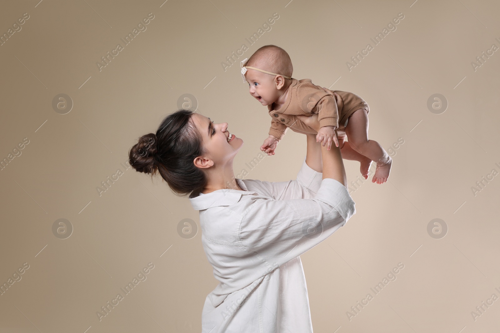 Photo of Beautiful mother with her cute baby on beige background