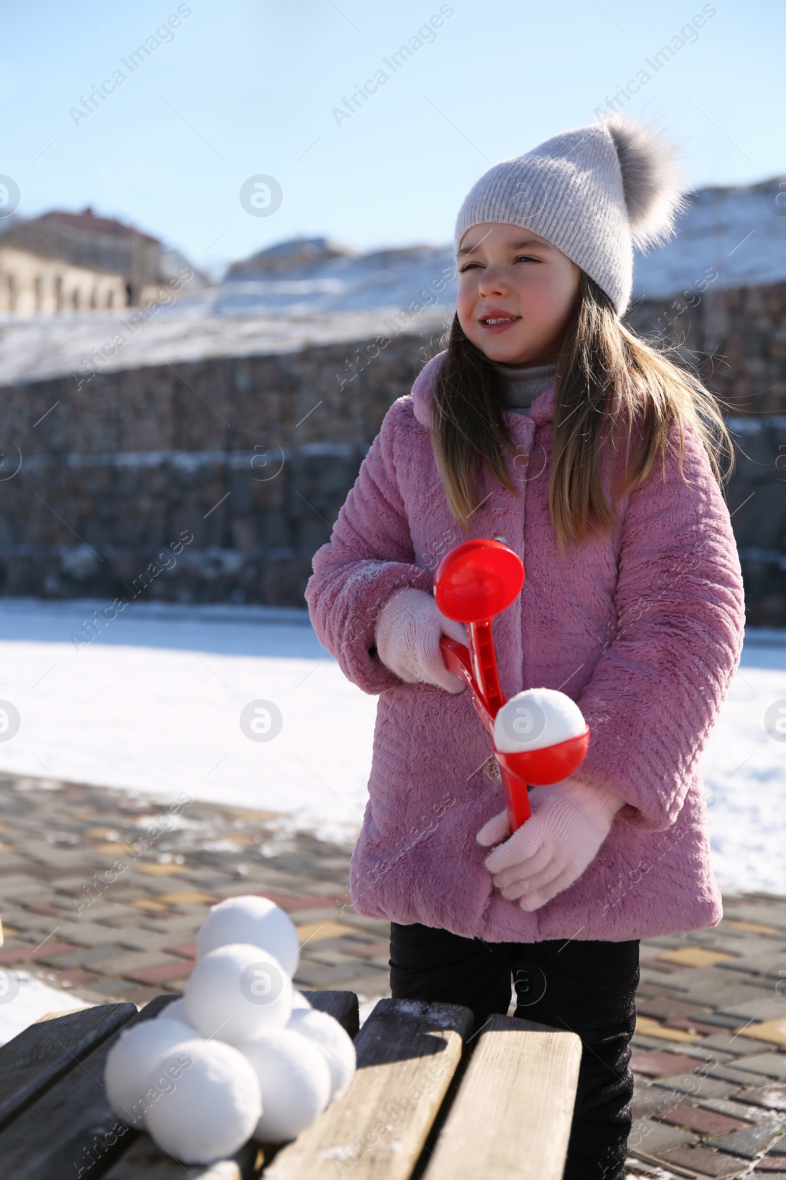 Photo of Cute little girl playing with snowball maker outdoors