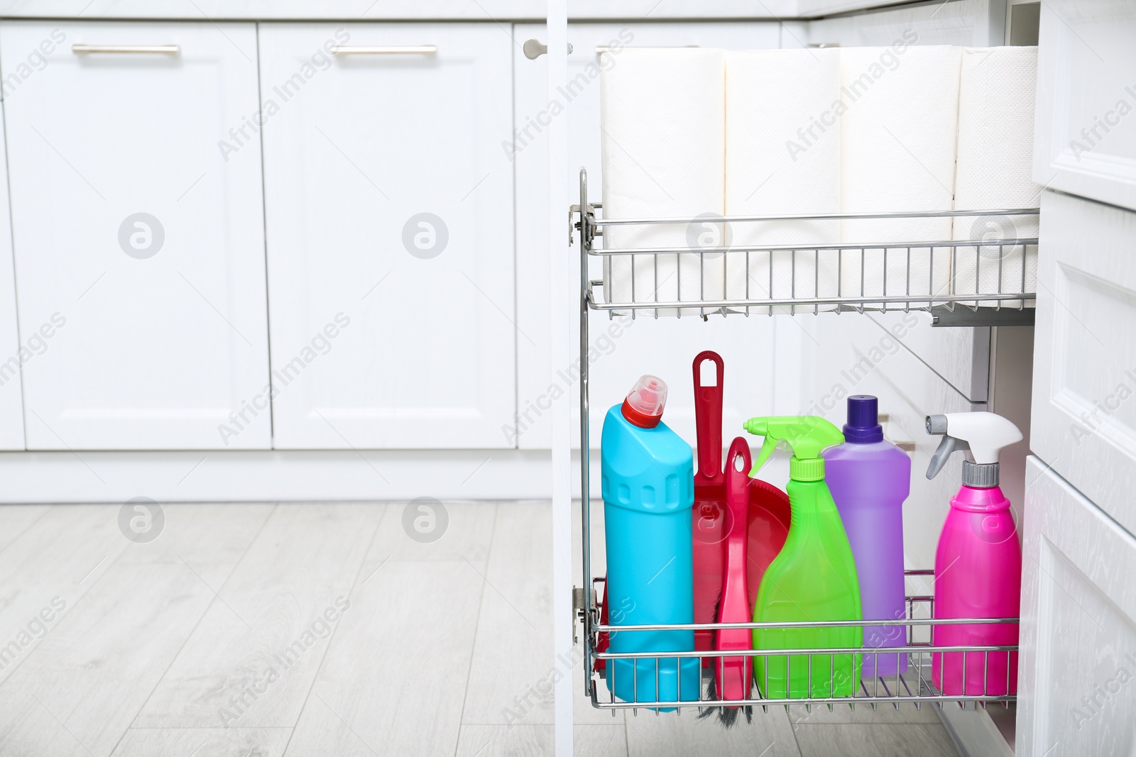 Photo of Open drawer with different cleaning supplies in kitchen, space for text