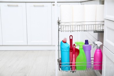 Open drawer with different cleaning supplies in kitchen, space for text