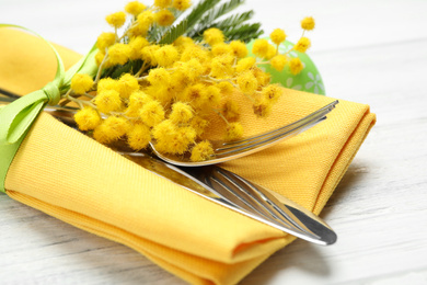 Photo of Cutlery set with floral decor on white wooden table, closeup. Easter celebration